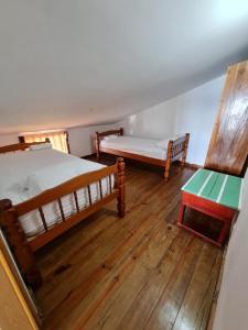 two beds and a table in a room with wooden floors at Hotel Caribbean View in Bocas Town