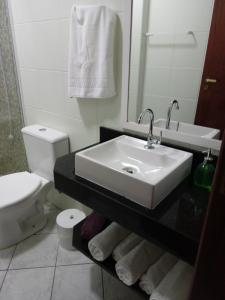 a white bathroom with a sink and a toilet at Apto. 2 quartos em Bombinhas (60 m da praia) in Bombinhas +10 photos