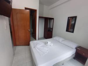 Un dormitorio con una cama blanca con un osito de peluche. en HOTEL LA FONTANA en Yopal
