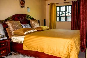 a bedroom with a bed with gold pillows and a window at Jaja's One Bedroom near Ciala Resort Kisumu in Kisumu