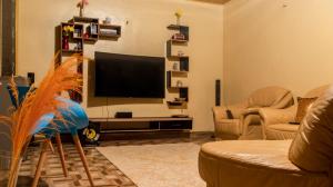 uma sala de estar com uma televisão de ecrã plano e 2 sofás em Jaja's One Bedroom near Ciala Resort Kisumu em Kisumu