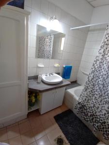een badkamer met een wastafel, een spiegel en een bad bij OliWine hostel in Maipú