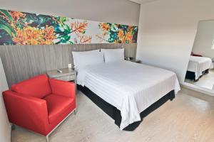 ein Schlafzimmer mit einem Bett und einem roten Stuhl in der Unterkunft GHL Hotel Neiva in Neiva