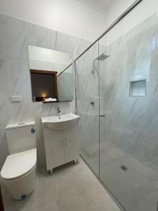 a bathroom with a shower and a toilet and a sink at Belgravia Mountain Guest House in Katoomba