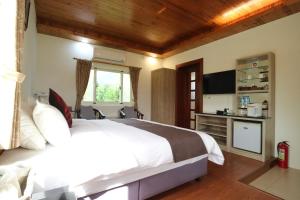 1 dormitorio con 1 cama blanca grande y TV en Countryside B&B, en Ruisui