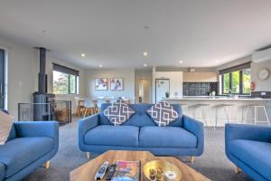 a living room with blue couches and a kitchen at 49 St James Avenue in Hanmer Springs