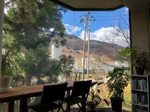 Zimmer mit einem Tisch und Stühlen sowie einem großen Fenster in der Unterkunft Petit Hotel Yukikkoso in Yuzawa