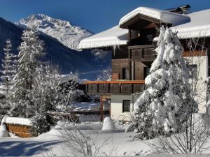 a snow covered building with a snow covered mountain at Appartements Eggenhofer in Sankt Jakob in Defereggen