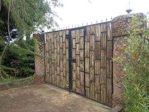 una valla con una puerta de madera en un patio en Plastic Bottles House en Entebbe