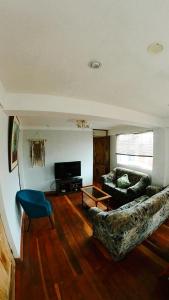 - un salon avec un canapé et une télévision dans l'établissement Arcopata Apartamentos, à Cusco