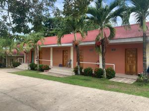 una casa con techo rosa y palmeras en Winter's Farm Resort, en Milagros