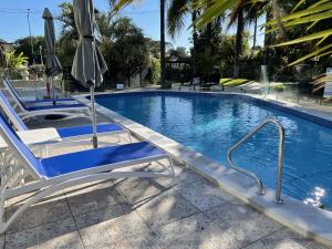 een zwembad met 2 ligstoelen en een parasol bij Burleigh Palms Holiday Apartments in Gold Coast