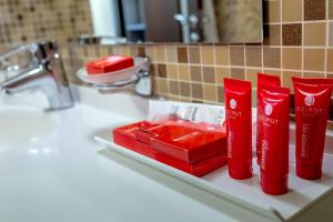 a bathroom sink with red toothbrushes and a box of lipstick at AZIMUT Hotel Siberia in Novosibirsk +37 photos