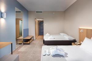 um quarto de hotel com duas camas e um espelho em The Aeolos Beach Hotel em Cidade de Kos