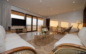 sala de estar con muebles blancos y TV de pantalla plana en Regency Sealine Camp en Mesaieed