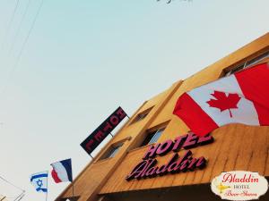 a building with a sign and a canadian flag on it at Aladdin Hotel Beer Sheva in Beer Sheva