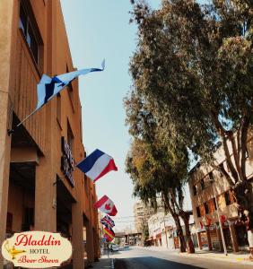 un gruppo di bandiere che volano sul lato di un edificio di Aladdin Hotel Beer Sheva a Beer Sheva