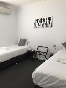 a bedroom with two beds and a chair in it at Central Motel Mudgee in Mudgee