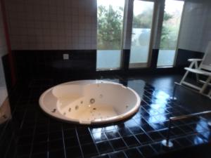 a bath tub in a black tiled room with windows at Gasthof Arutany in Nasu +96 photos