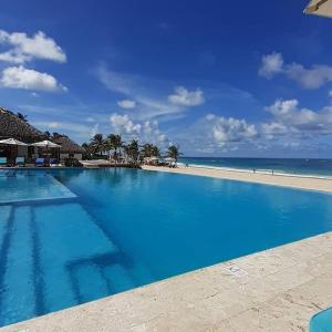 une grande piscine bleue à côté de la plage dans l'établissement Apartamento 120 Jardin Privado Cana Rock, à Punta Cana