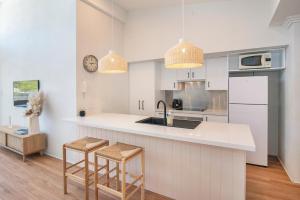 a kitchen with white cabinets and a counter with stools at Villa on Fearn in Margaret River Town