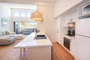 Una cocina con gabinetes blancos y una sala de estar. en Villa on Fearn, en Margaret River Town 6 fotos más