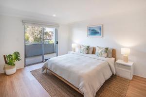 a white bedroom with a large bed and a sliding glass door at Villa on Fearn in Margaret River Town