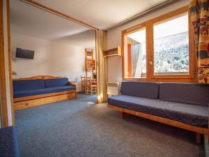 ヴァルモレルにあるAppartement Valmorel, 1 pièce, 4 personnes - FR-1-356-254の青いソファ2台と窓が備わる客室です。