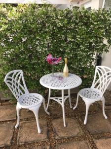 a table and two chairs with a vase of flowers on it at Summer Place, Southern Cross Drive, Constantia, Cape Town in Cape Town