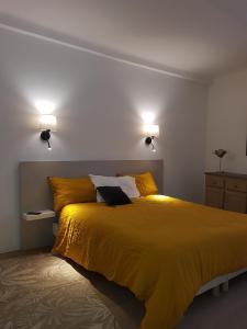 a bedroom with a large yellow bed with two lights at Maison de ville Forum Julii in Fréjus