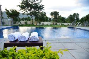 two rolled towels on a bench next to a swimming pool at The Q Villa, Udaipur in Udaipur +5 photos