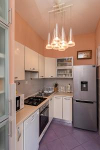 Apartment Van Gogh في دوبروفنيك: مطبخ بدولاب أبيض وأجهزة بيضاء
