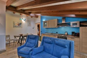 a living room with blue chairs and a kitchen at Agriturismo Al Lambic in Tignale
