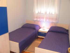2 camas en una habitación pequeña con sábanas moradas en Apartments Villa Ceres, en Klek
