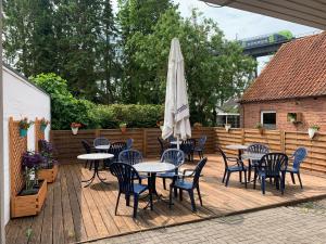 una terraza de madera con mesas y sombrilla en Hotel O'felder, en Osterrönfeld