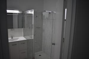 a bathroom with a glass shower and a sink at Riviana Motel in Deniliquin