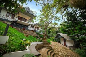 a house with a staircase leading up to a house at Golden Fern Resort in Kanthalloor