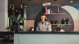 a woman sitting at a counter in a coffee shop at Holiday Inn - the niu, Cure Erlangen, an IHG Hotel in Erlangen