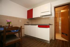 a small kitchen with white cabinets and a table at Apartments Neda - Poreč South in Poreč