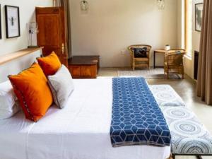a bedroom with a bed with orange and blue pillows at Eclectic Safari Lodge in Mabula
