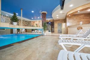 a pool with white lounge chairs in a hotel lobby at Amici Grand Hotel in Krasnodar