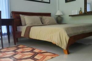 ein Schlafzimmer mit einem großen Bett mit einem Tisch und einem Teppich in der Unterkunft Rose-Bud Cottage in Ko Chang