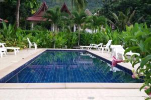 einen Pool in einem Resort mit weißen Stühlen und Bäumen in der Unterkunft Rose-Bud Cottage in Ko Chang + 26 Fotos