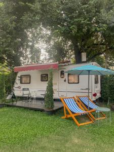 a rv with a table and two chairs and an umbrella at Nice Nite Campervans in Phra Nakhon Si Ayutthaya