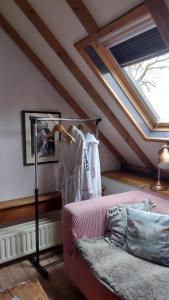 レッケルケルクにあるTheetuin Onder de Pannenのピンクのソファと窓が備わる屋根裏部屋