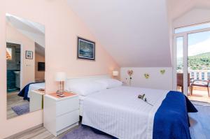 a white bedroom with a bed and a balcony at Guest House Avdic in Dubrovnik