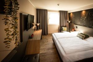 um quarto de hotel com uma cama e uma televisão em LOGINN Hotel Stuttgart Zuffenhausen em Stuttgart