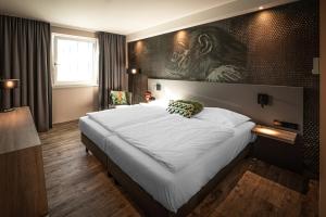 a bedroom with a large bed with a monkey painting on the wall at LOGINN Hotel Stuttgart Zuffenhausen in Stuttgart