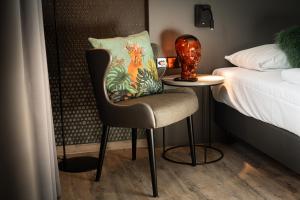 a bedroom with a chair next to a bed at LOGINN Hotel Stuttgart Zuffenhausen in Stuttgart