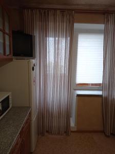 um quarto com uma janela, uma televisão e um frigorífico em 1к. Апартаменты НСК на ул.Блюхера 67/1 em Novosibirsk